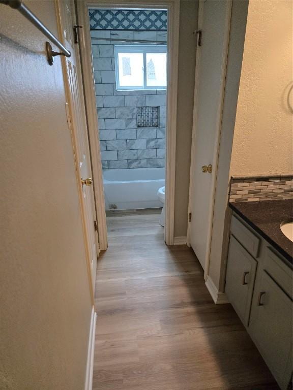 full bathroom with hardwood / wood-style floors, vanity, toilet, and tiled shower / bath combo