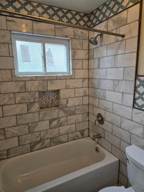 bathroom with toilet and tiled shower / bath