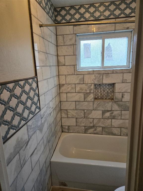 bathroom featuring a wealth of natural light and tiled shower / bath combo