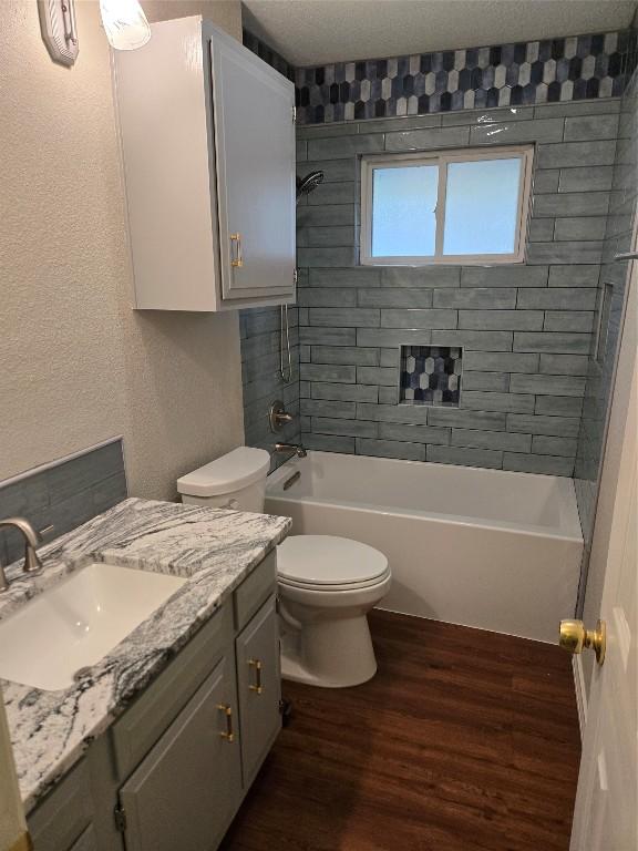 full bathroom featuring hardwood / wood-style floors, vanity, toilet, and tiled shower / bath combo