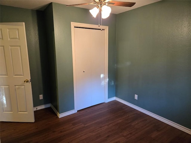 unfurnished bedroom with ceiling fan, a closet, and dark wood-type flooring