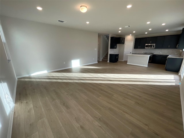 unfurnished living room featuring light hardwood / wood-style floors and sink