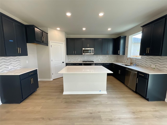 kitchen featuring appliances with stainless steel finishes, a center island, light hardwood / wood-style floors, sink, and decorative backsplash