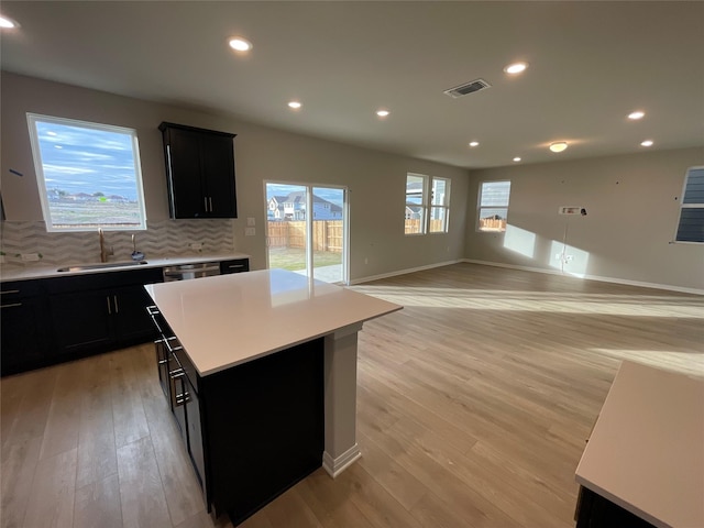 kitchen featuring sink, decorative backsplash, light hardwood / wood-style floors, and a center island