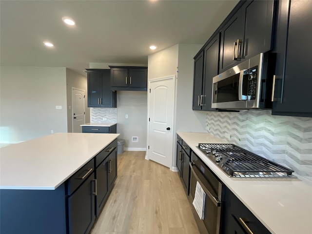 kitchen with decorative backsplash, a center island, stainless steel appliances, and light wood-type flooring