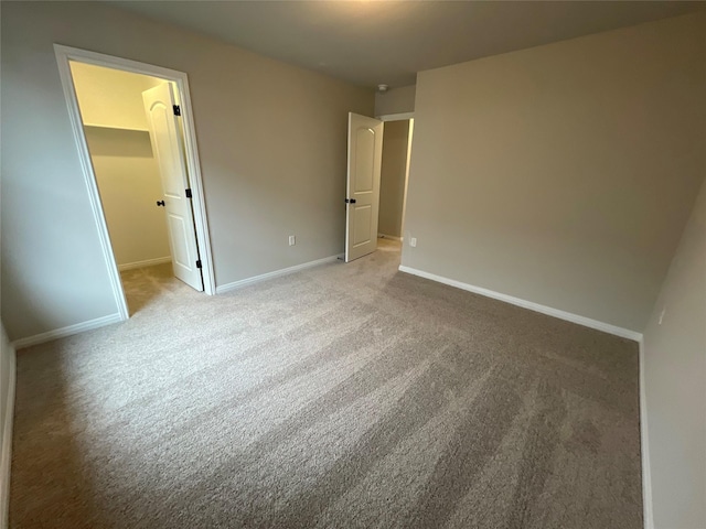 unfurnished bedroom featuring a spacious closet, a closet, and light carpet