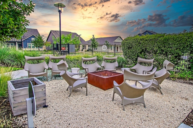 patio terrace at dusk featuring an outdoor fire pit and fence