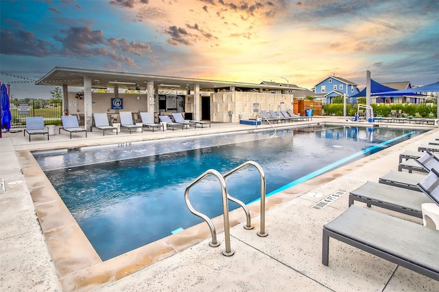 pool at dusk with a patio area