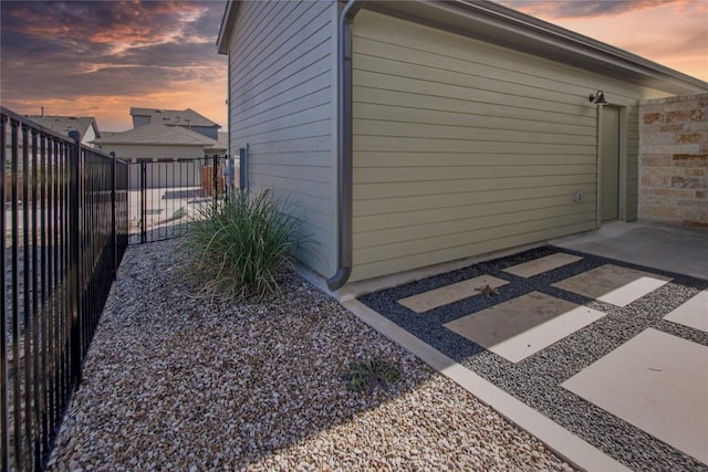 property exterior at dusk with a patio area and fence