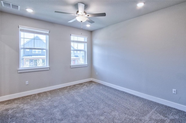 carpeted spare room with baseboards, visible vents, and ceiling fan