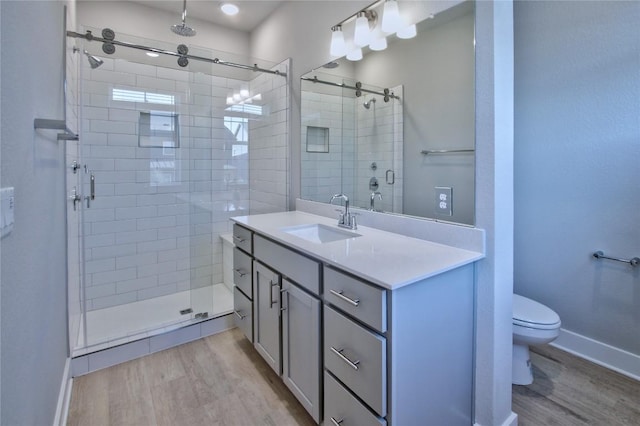 bathroom featuring wood-type flooring, walk in shower, vanity, and toilet