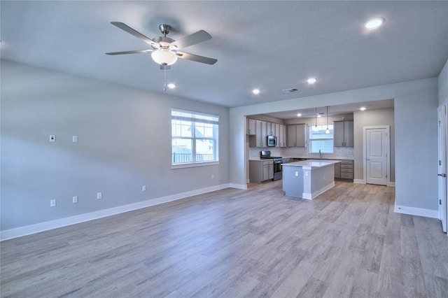 kitchen with a center island, hanging light fixtures, light wood-type flooring, ceiling fan, and stainless steel appliances