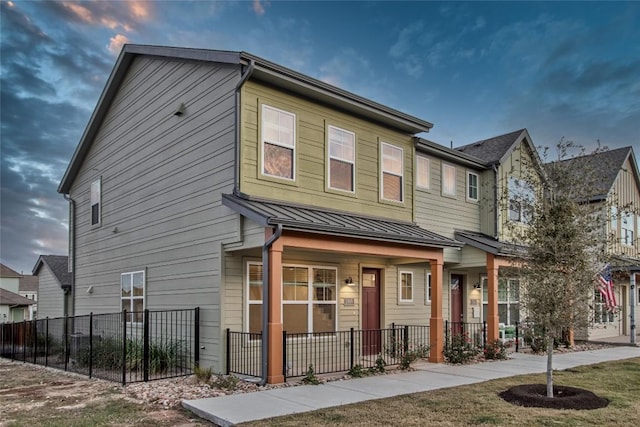 multi unit property featuring a standing seam roof, a fenced front yard, metal roof, and a porch