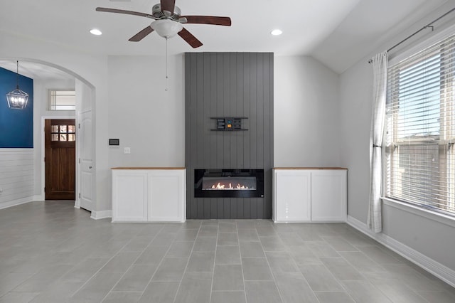 unfurnished living room with arched walkways, a fireplace, recessed lighting, vaulted ceiling, and ceiling fan