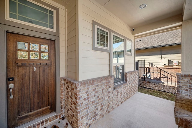 entrance to property featuring covered porch and brick siding