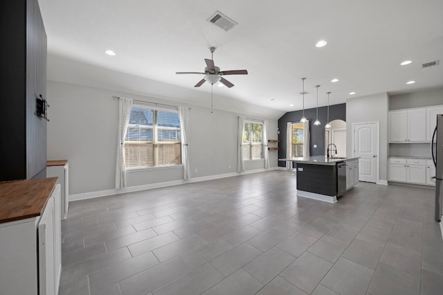 kitchen with ceiling fan, sink, tile patterned floors, an island with sink, and pendant lighting