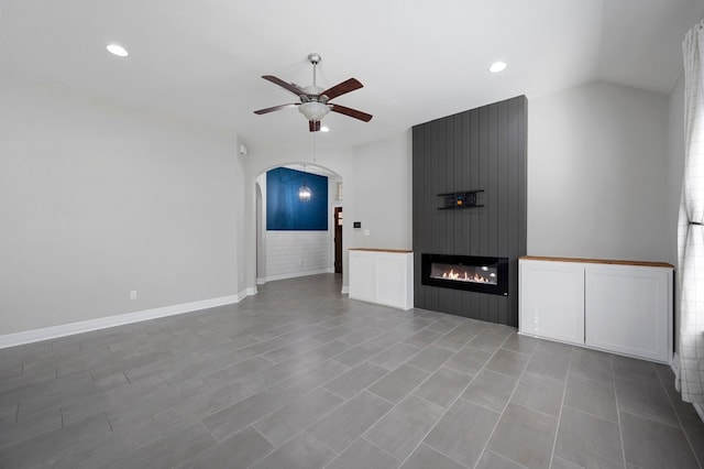 unfurnished living room featuring ceiling fan, lofted ceiling, and a fireplace