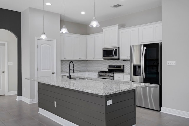 kitchen with white cabinets, sink, stainless steel appliances, and a center island with sink