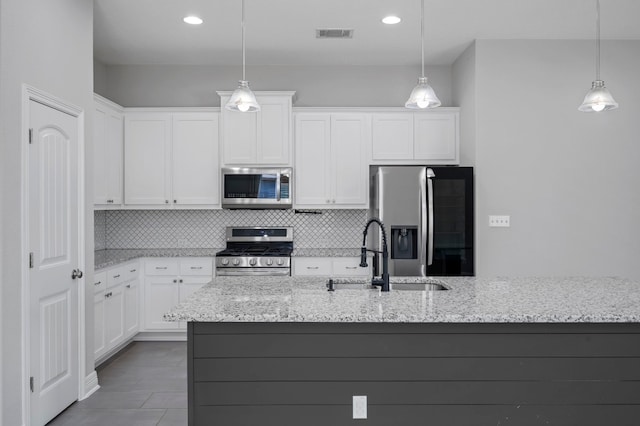 kitchen with light stone counters, stainless steel appliances, white cabinetry, and sink