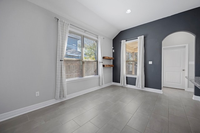 unfurnished room featuring light tile patterned floors and vaulted ceiling