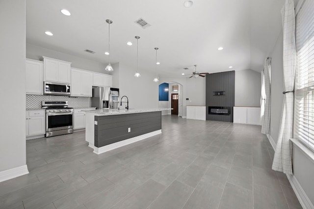 kitchen with pendant lighting, white cabinets, a kitchen island with sink, and appliances with stainless steel finishes