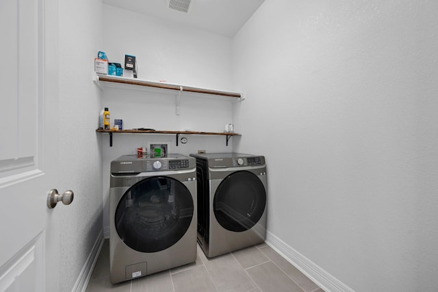 washroom with light tile patterned floors, visible vents, washing machine and dryer, laundry area, and baseboards