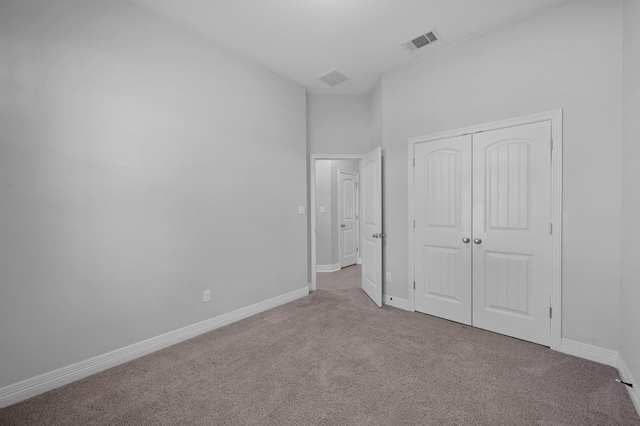 unfurnished bedroom with a closet, light colored carpet, visible vents, and baseboards