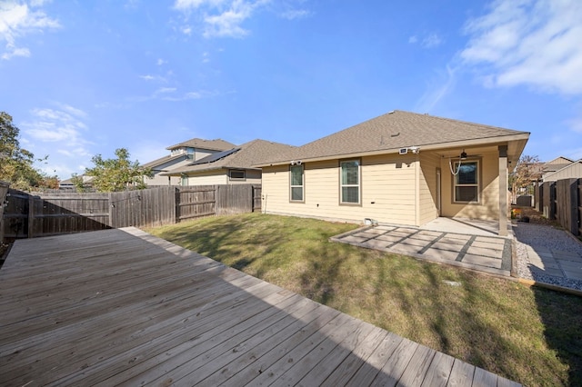 rear view of property with a deck, ceiling fan, and a lawn