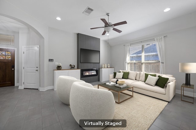 living room with ceiling fan, a large fireplace, and vaulted ceiling