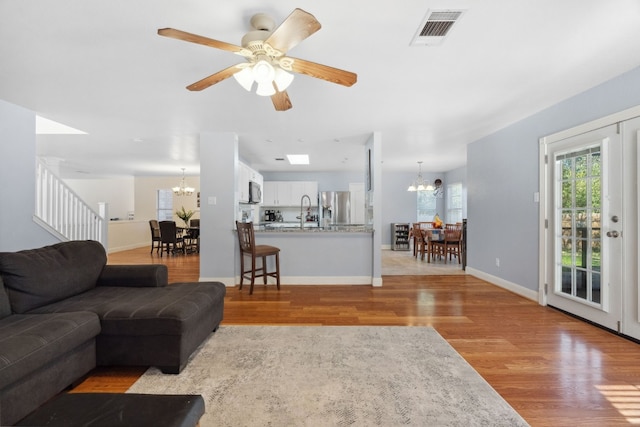 living room with ceiling fan with notable chandelier and light wood-type flooring