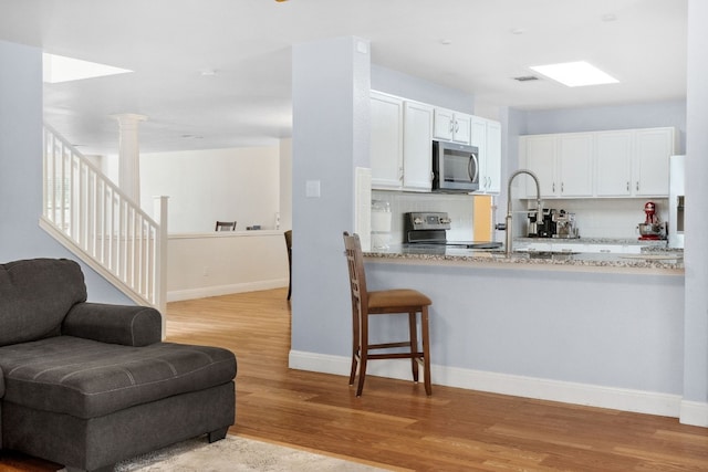 kitchen featuring backsplash, white cabinetry, light wood-type flooring, and appliances with stainless steel finishes