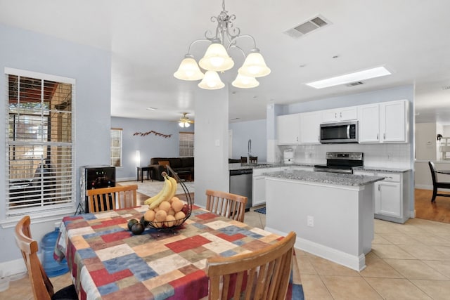 tiled dining space with sink and ceiling fan with notable chandelier