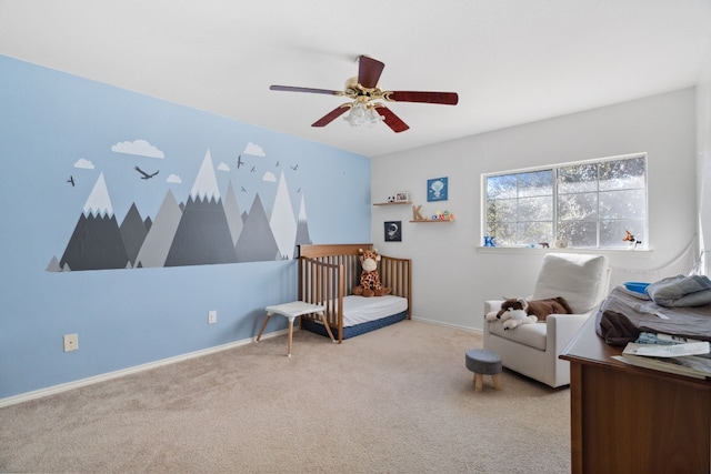 bedroom with a crib, light carpet, and ceiling fan