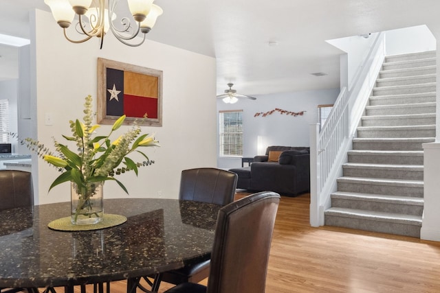 dining area featuring light hardwood / wood-style flooring and ceiling fan with notable chandelier