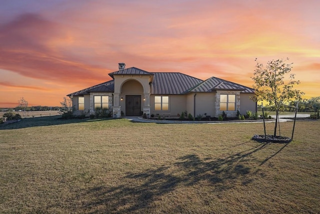 view of front of house with a standing seam roof, metal roof, stone siding, and a front lawn