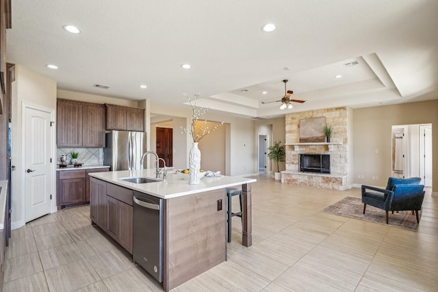 kitchen featuring a center island with sink, a raised ceiling, stainless steel appliances, and sink