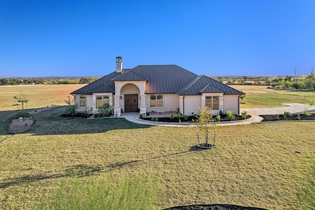 view of front facade with metal roof, a chimney, stucco siding, a front lawn, and a standing seam roof