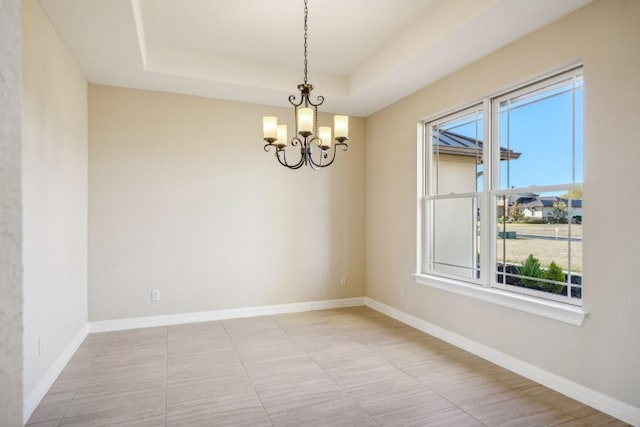 unfurnished room featuring a tray ceiling and an inviting chandelier