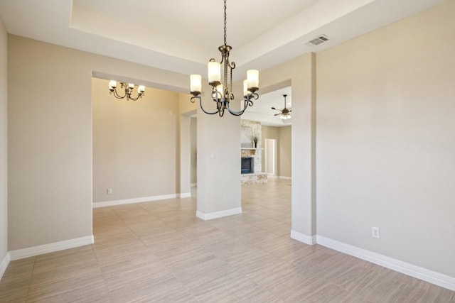 unfurnished room featuring ceiling fan with notable chandelier and a stone fireplace