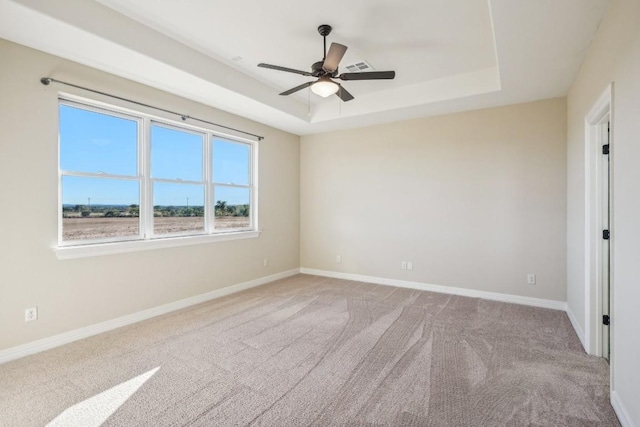 empty room with carpet, a tray ceiling, and ceiling fan