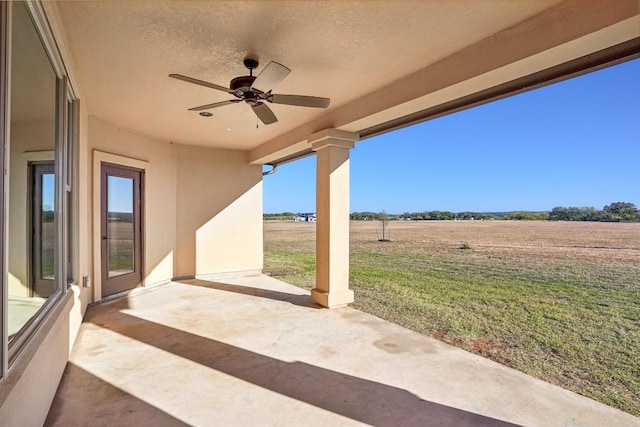 view of patio / terrace featuring ceiling fan and a rural view