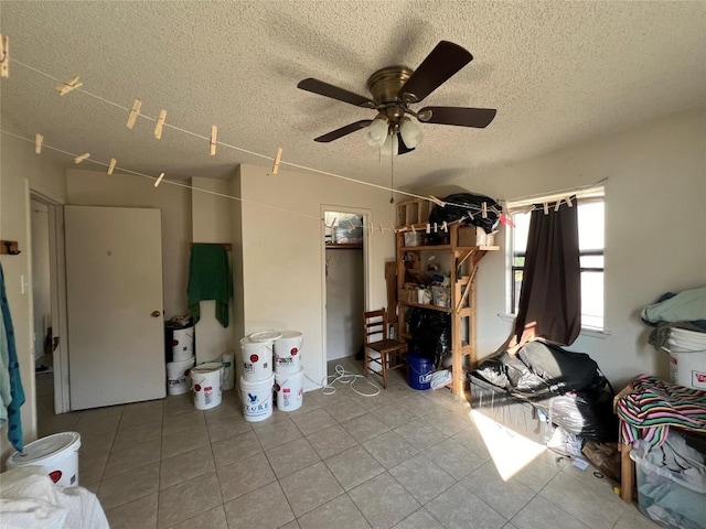 interior space featuring ceiling fan, light tile patterned flooring, and a textured ceiling