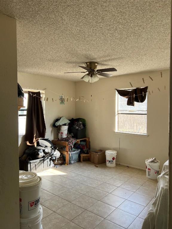 interior space with ceiling fan, tile patterned flooring, and a textured ceiling