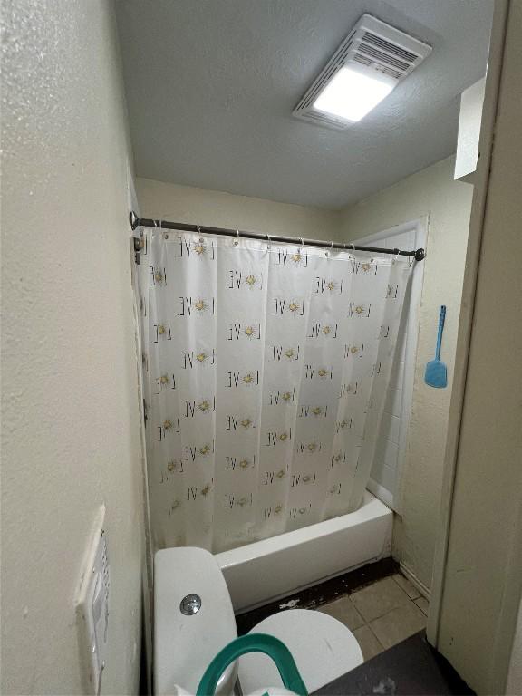 bathroom featuring tile patterned flooring, toilet, and shower / tub combo