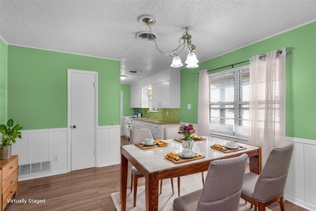 dining room with light hardwood / wood-style floors, a textured ceiling, and a chandelier