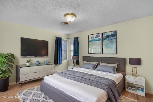 bedroom featuring a textured ceiling and light hardwood / wood-style floors