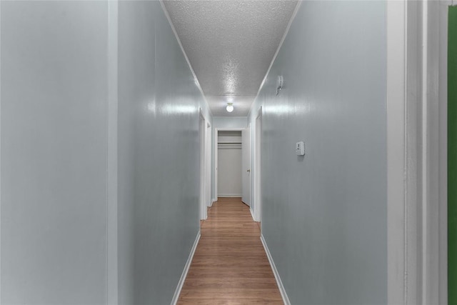 hall with light hardwood / wood-style flooring and a textured ceiling