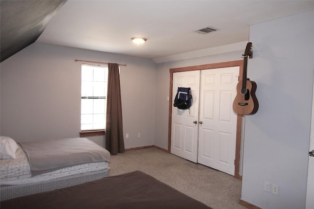 bedroom featuring light colored carpet, lofted ceiling, and a closet