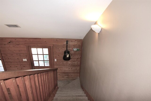 stairs featuring carpet floors and wood walls