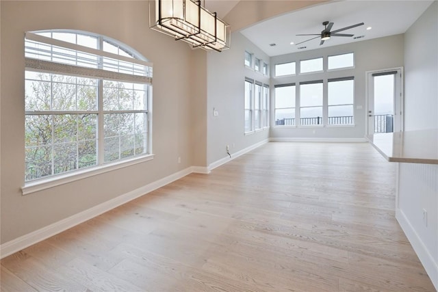 interior space with ceiling fan with notable chandelier and light hardwood / wood-style floors